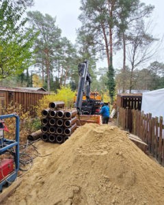 Bauarbeiter verlegt Rohre mit Bagger im Gartenbereich