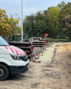 Baustelle mit Rohren und Baufahrzeug am Straßenrand